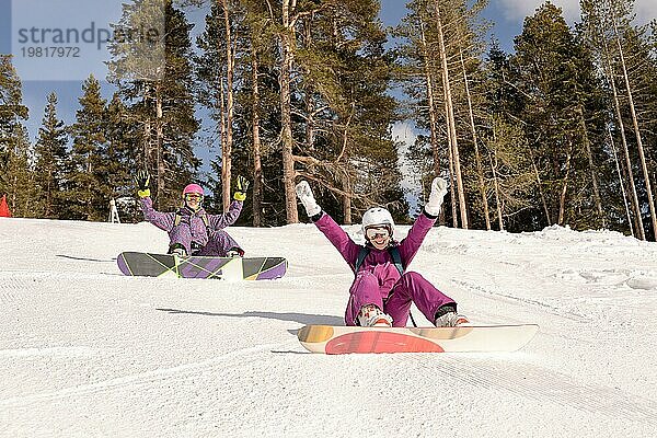 Zwei Freunde sitzen auf der Skipiste  Snowboarder Mädchen