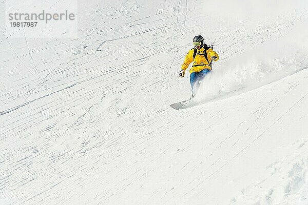 Ein Mann  ein Snowboard Freerider  fährt mit hoher Geschwindigkeit von einer Piste ins Hinterland und hinterlässt eine Spur aus Pulverschnee. Das Konzept der Freeride Kultur und Backcountry Destinationen im Snowboarding