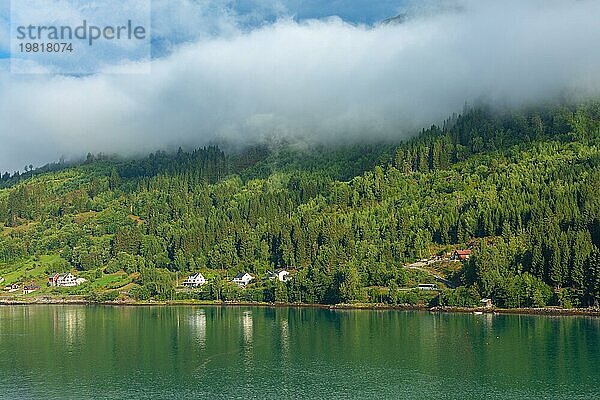 Norwegische Dorflandschaft mit Fjord  Sommerbergen  Wolken und bunten Häusern in Olden  Norwegen  Europa