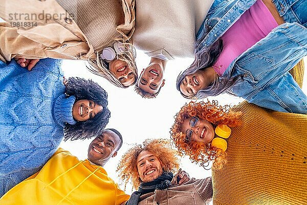 Niedriger Blickwinkel auf multiethnische Menschen  die einen Kreis bilden und in die Kamera lächeln