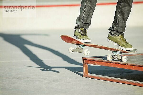 Der junge Mann auf einem Skateboard in einem Handbuch auf einer Rampe auf dem Hintergrund der Häuser