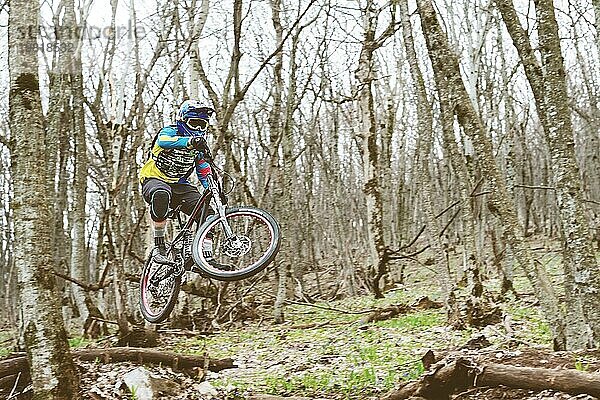 Ein Mountainbikefahrer springt von einem Sprungbrett in einem nebligen Wald  im Kaukasusgebirge  Downhill Fahrer