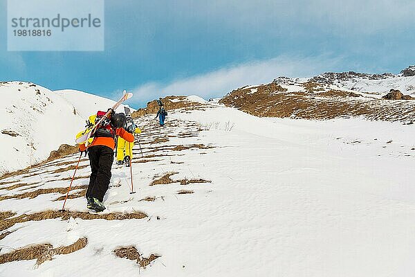 Eine Gruppe von drei Freeridern erklimmt den Berg  um an den wilden Hängen des Nordkaukasus Backcountry Skiing zu betreiben. Das Konzept des Backcountry Freeride. Nordkaukasus. Russland