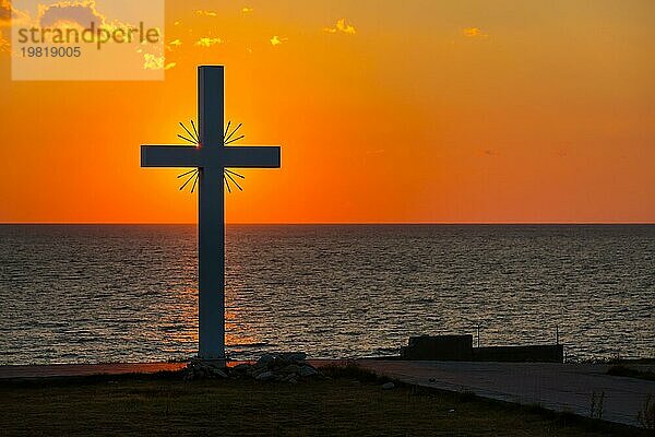 Silhouette eines Kreuzes bei Sonnenaufgang oder Sonnenuntergang mit Lichtstrahlen und Meerespanorama  Griechenland  Europa