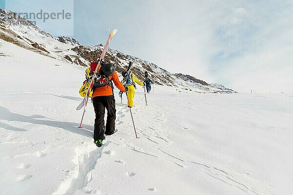 Eine Gruppe von drei Freeridern erklimmt den Berg  um an den wilden Hängen des Nordkaukasus Backcountry Skiing zu betreiben. Das Konzept des Backcountry Freeride. Nordkaukasus. Russland