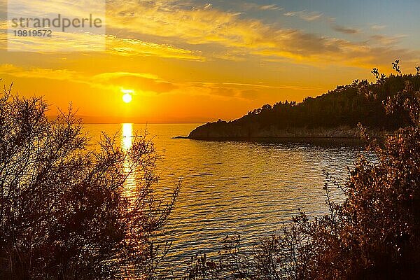 Goldener Sonnenuntergang über dem Meer in Griechenland Küste mit Wolken und Bäume Silhouette