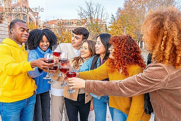 Diverse junge Leute  die auf der Straße stehen und mit Rotwein anstoßen