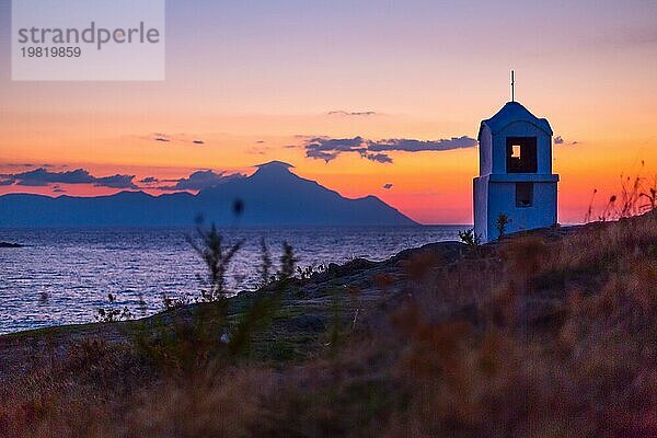 Kleine griechische Kapelle und Silhouette des Berges Athos bei Sonnenaufgang oder Sonnenuntergang bunten Himmel in Griechenland