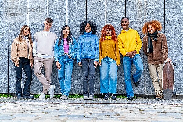 Porträt einer multiethnischen Gruppe von Freunden  die sich an eine Hauswand lehnen