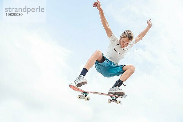 Junge angestrengte Skateboarderin im Hochsprung gegen den Himmel