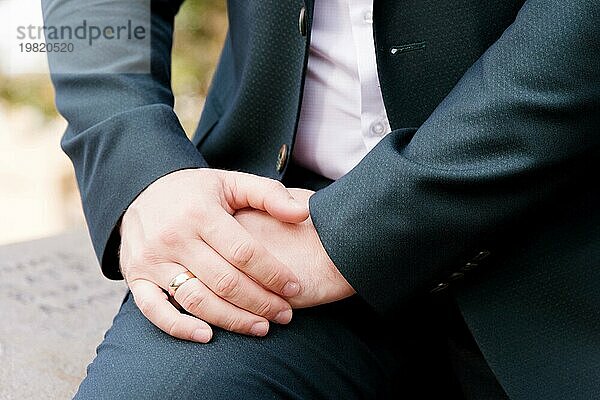 Nahaufnahme der Hand eines in der Natur sitzenden Mannes vor dem Hintergrund eines Felsens