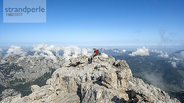 Bergsteiger rastet auf einem Felsen mit Bergpanorama  Bergtour auf den Gipfel des Hochkalter  Hochkalter Überschreitung  Berchtesgadener Alpen  Bayern  Deutschland  Europa