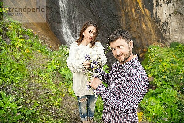 Ein verliebtes Paar von Hipstern hält einen Hochzeitsstrauß aus Blumen