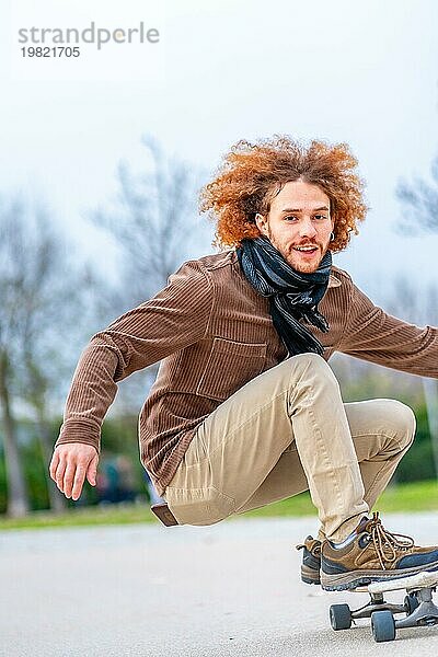 Vertikales Foto mit Kopierbereich eines glücklichen jungen Mannes beim Skateboardfahren in einem Park