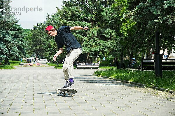 Langhaariger Skater Teenager in TShirt und Turnschuhmütze springt den Ollie vor dem Hintergrund eines stürmischen Himmels über der Stadt