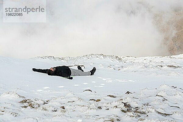 Junger lateinischer Junge  der im Schnee liegt  mitten im Schneesturm