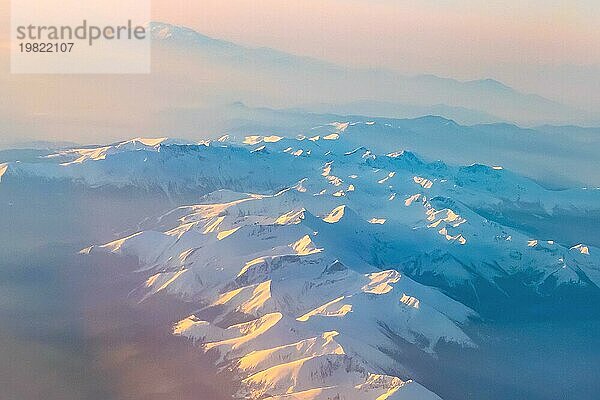 Luftaufnahme von bunten Sonnenaufgang über Berge Schneespitzen und Silhouetten  aus dem Flugzeug geschossen