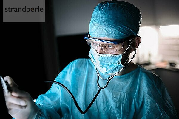 Männlicher Chirurg in Uniform bei der Arbeit mit einem Stethoskop in einer Arztpraxis