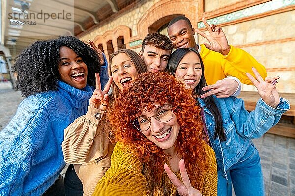 Junge unterschiedliche Freunde gestikulieren erfolgreich  während sie ein Selfie in der Stadt Straße