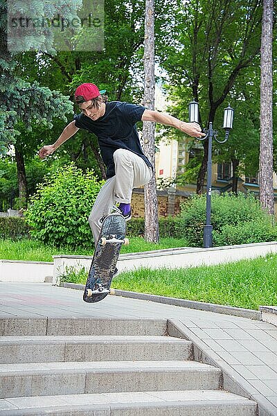 Langhaariger Skater Teenager in TShirt und Turnschuhmütze springt den Ollie vor dem Hintergrund eines stürmischen Himmels über der Stadt