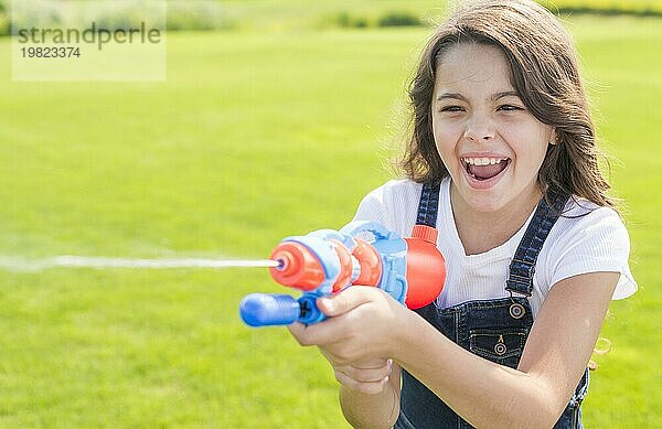 Smileymädchen spielt mit Wasserpistole