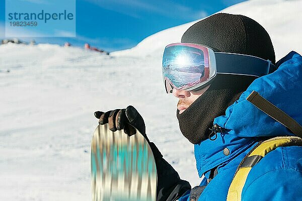 Ein professioneller Snowboarder steht mit seinem Snowboard vor der Kulisse des schlafenden Vulkans Elbrus. Nordkaukasus. Beschaffung für Werbung oder Plakat mit Copy Space. Konzept von Wintersport und Erholung