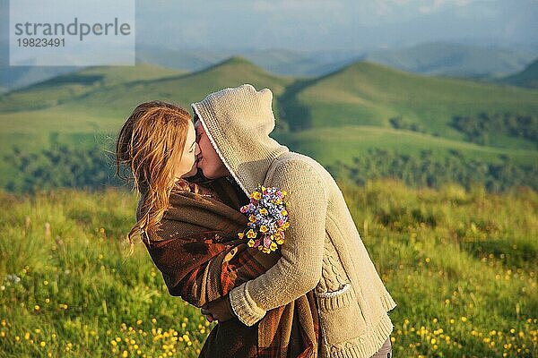 Junges glückliches Paar  das sich in der Natur vor der schönen kaukasischen Landschaft küsst. Das Konzept einer glücklichen jungen Familie und die Kommunikation der Jugend mit der Natur