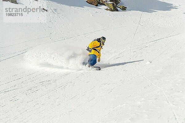 Ein Mann  ein Snowboard Freerider  fährt mit hoher Geschwindigkeit von einer Piste ins Hinterland und hinterlässt eine Spur aus Pulverschnee. Das Konzept der Freeride Kultur und Backcountry Destinationen im Snowboarding