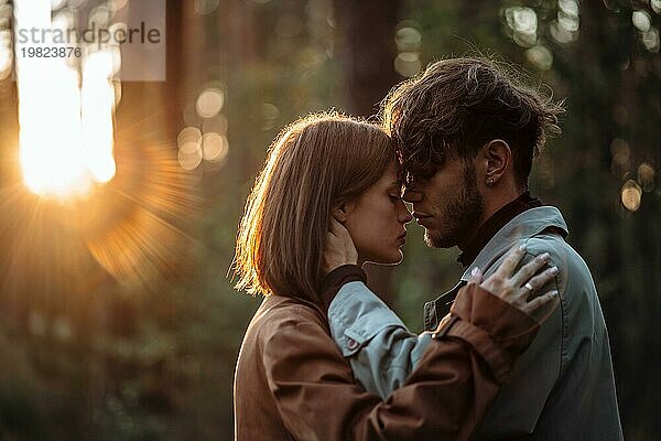 Schöne modische Paar in der Liebe Umarmungen im Wald bei Sonnenuntergang im Herbst  romantische Datum in Regenmäntel  trendy Mann und Frau