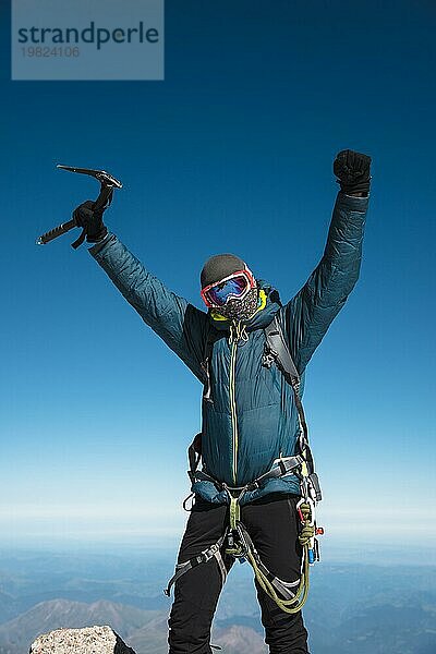 Professioneller Führer Wanderer auf dem Gipfel des Felsens mit erhobenen Händen freut sich über den nächsten Erfolg des Aufstiegs an einem sonnigen Nachmittag