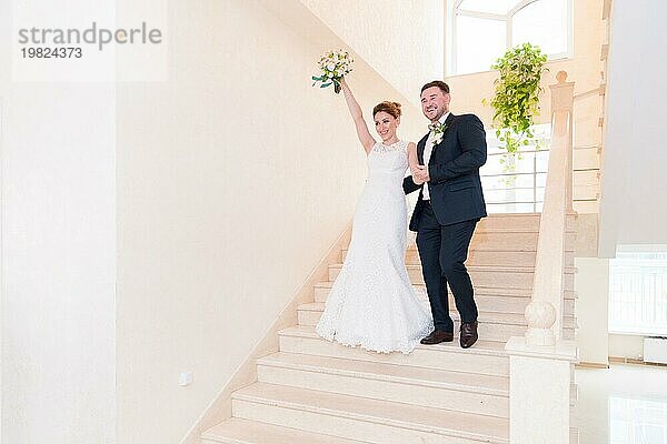 Ein frisch vermähltes Paar geht die Treppe des Standesamtes hinunter und begrüßt die Menschen  die ihnen begegnen  mit Lächeln und Gesten. Das Konzept der Eheschließung auf dem Standesamt