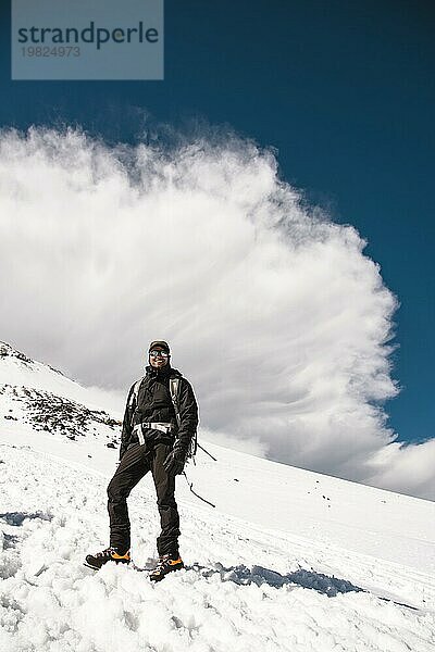 Professionelle Bergsteiger gehen auf den Hang des Elbrus vor dem Hintergrund der großen Sturmwolke