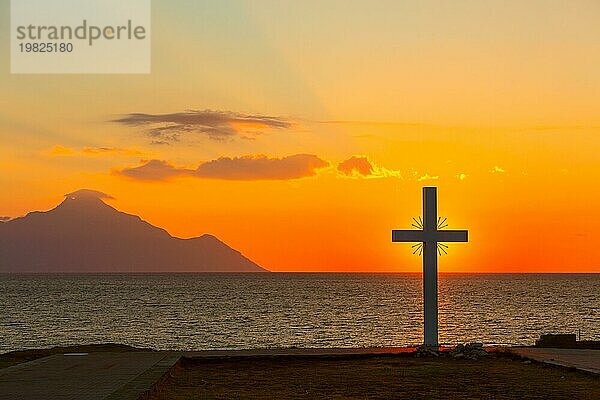 Silhouette eines Kreuzes bei Sonnenaufgang oder Sonnenuntergang mit Lichtstrahlen und Meerespanorama  Athos  Griechenland  Europa