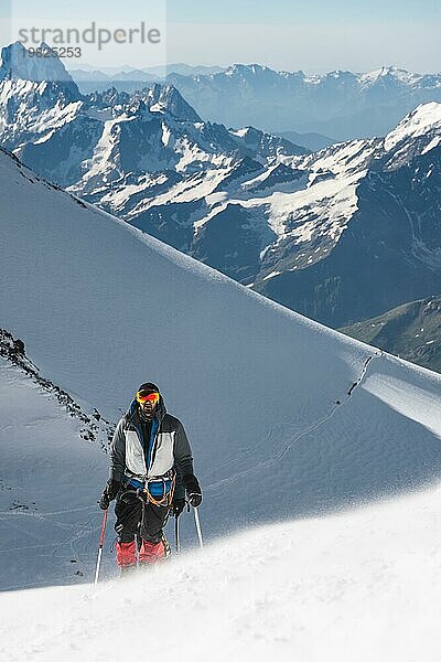 Professionelle Bergsteiger besteigen den westlichen Gipfel des Elbrus vor dem Hintergrund des kaukasischen Gebirgskamms und der schneebedeckten Gipfel des Kaukasusgebirges