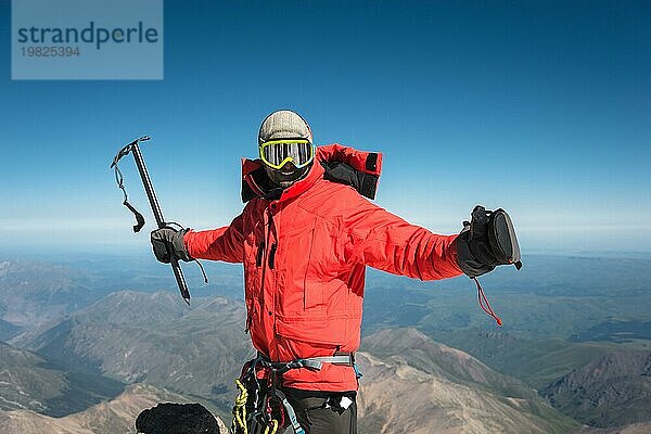 Profi Wanderer auf dem Gipfel des Felsens mit erhobenen Händen freut sich über den nächsten Sieg des Aufstiegs an einem sonnigen Nachmittag