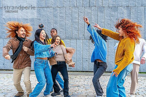 Fröhliche multiethnische Freunde tanzen aufgeregt in der Stadt zusammen