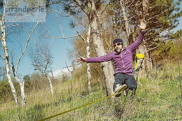 Ein Mann im Alter von auf der Slackline sitzend  das Gleichgewicht haltend und das Leben genießend