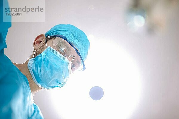 Männlicher Chirurg Arzt im Operationssaal  der den Patienten betrachtet