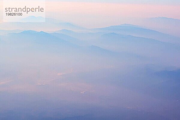 Luftaufnahme von rosa und blaün Sonnenuntergang  Sonnenaufgang über Berge Silhouetten  Schuss aus dem Flugzeug