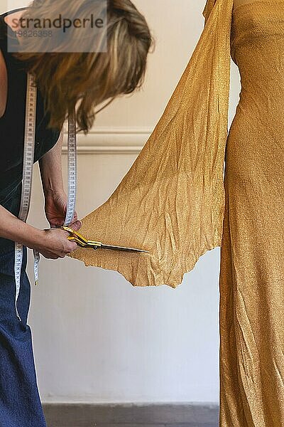 Modedesignerin arbeitet mit einer Textilschere an einem Kleidungsentwurf. Vertikale Aufnahme