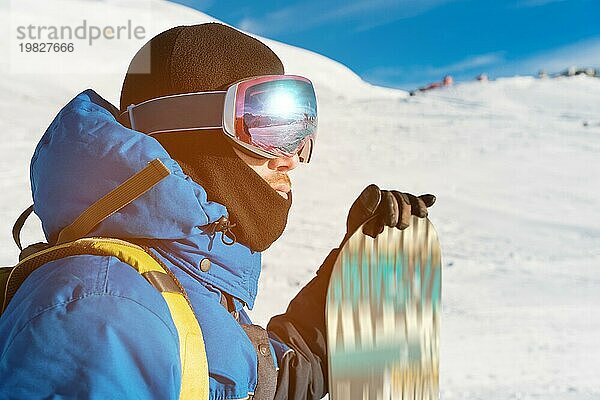 Ein professioneller Snowboarder steht mit seinem Snowboard vor der Kulisse des schlafenden Vulkans Elbrus. Nordkaukasus. Beschaffung für Werbung oder Plakat mit Copy Space. Konzept von Wintersport und Erholung