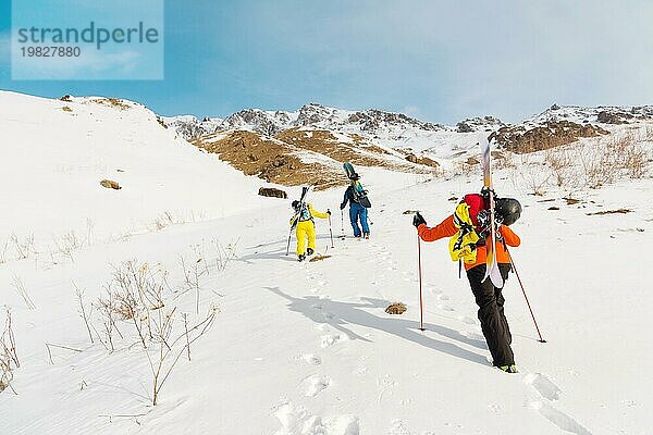 Eine Gruppe von drei Freeridern erklimmt den Berg  um an den wilden Hängen des Nordkaukasus Backcountry Skiing zu betreiben. Das Konzept des Backcountry Freeride. Nordkaukasus. Russland