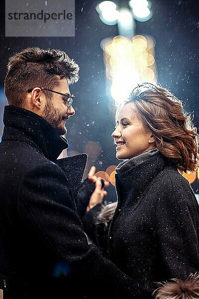 Junge schöne Paar in der Liebe tanzen in der Stadt unter Schneefall auf valentine's day