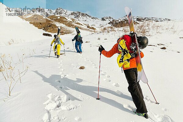 Eine Gruppe von drei Freeridern erklimmt den Berg  um an den wilden Hängen des Nordkaukasus Backcountry Skiing zu betreiben. Das Konzept des Backcountry Freeride. Nordkaukasus. Russland