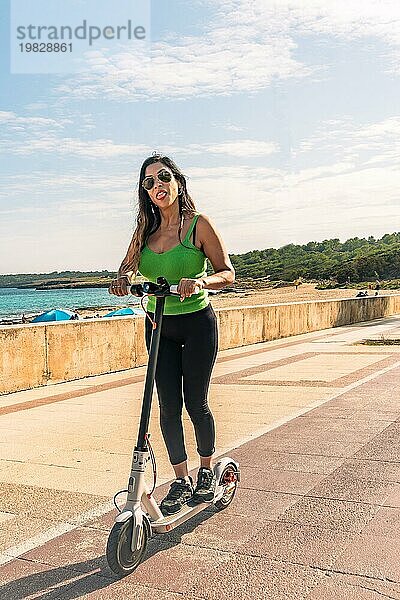 Frau reitet Elektroroller  glücklich und Sommer Fahrt auf tropischen Insel Strand Resort für Urlaub. Stadt  Straße und umweltfreundliche Transport  Spaß auf escooter im Urlaub in Mallorca  Baleareninsel