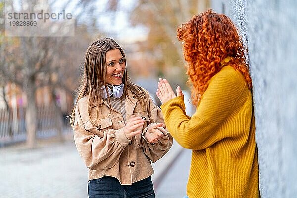 Zwei moderne weibliche Freunde lächelnd und im Gespräch auf der Straße