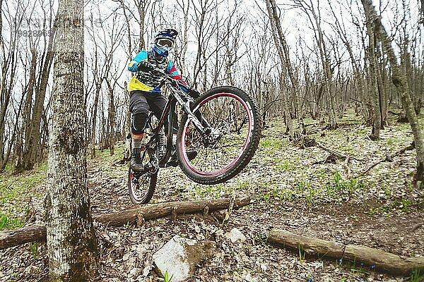 Ein Mountainbikefahrer springt von einem Sprungbrett in einem nebligen Wald  im Kaukasusgebirge  Downhill Fahrer