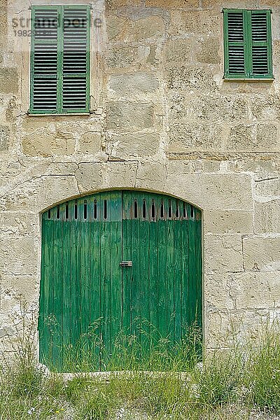 Fassade eines alten Bauernhofs. Tür und Fenster aus Naturholz Textur  Steinmauern von Mares  typisch natürlich von Mallorca  ländliches Haus für Agrotourismus  verschiedene Fenster  Landhaus