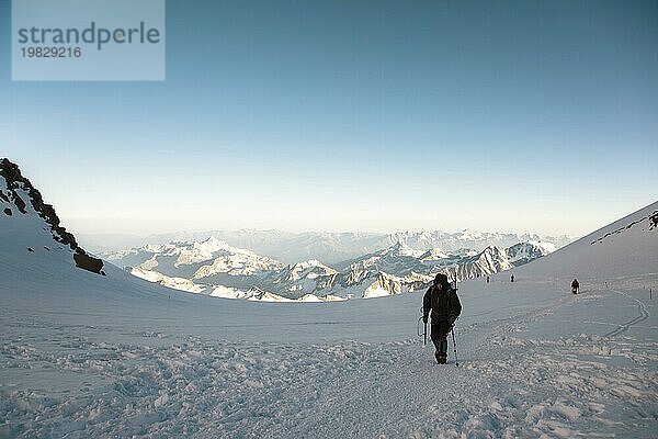 Professionelle Bergsteiger besteigen den westlichen Gipfel des Elbrus vor dem Hintergrund des kaukasischen Gebirgskamms und der schneebedeckten Gipfel des Kaukasusgebirges