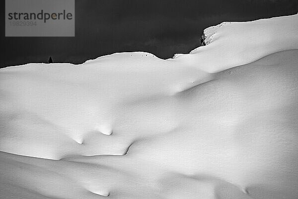 Weitläufige Hochfläche mit tief verschneiten Bergen im Hintergrund und dramatischem Himmel  Berlinger Köpfle  Ritzlern Kleinwalsertal  Vorarlberg  Österreich  Europa